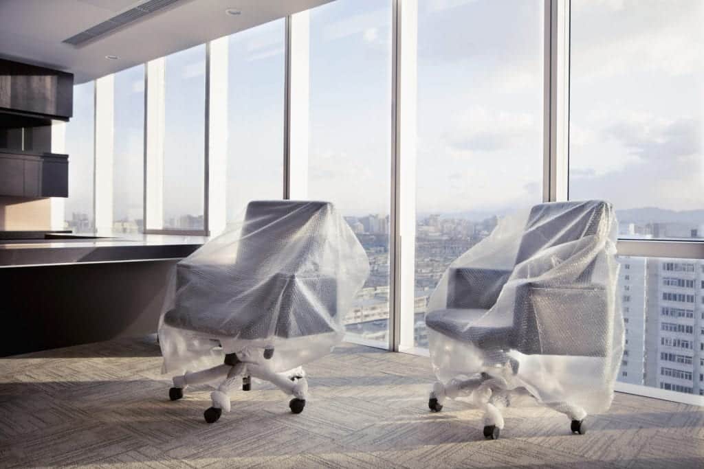 Desk chairs wrapped with bubble wrap in executive office